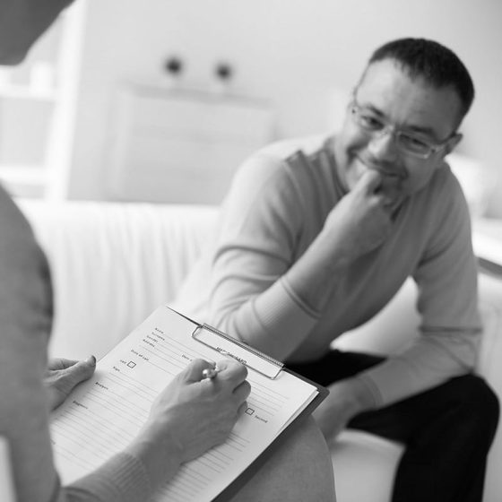 Female psychologist consulting mature man during psychological therapy session